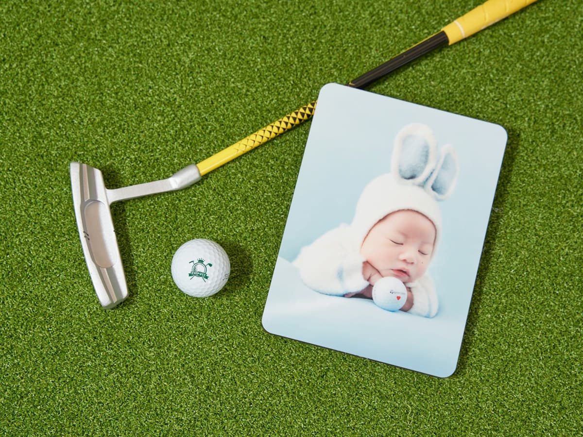 A golf putter and ball on green turf; illustrative editorial photography